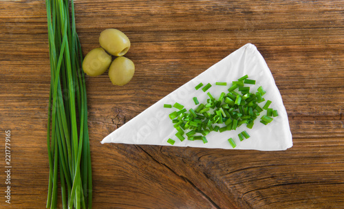 Round Soft Cheese with Chives and Olives on Wooden Table
