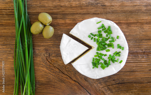 Round Soft Cheese with Chives and Olives on Wooden Table