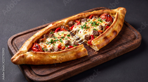 Freshly baked turkish pide with meat and melted cheese served on a