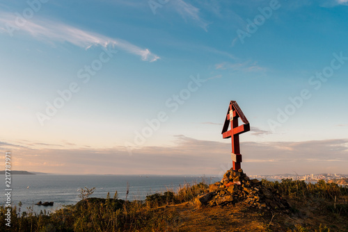 Fotografie Wooden Orthodox cross on a coastal hill with Vladivostok skyline and the sea in the distance, Russky Island, Primorsky Krai, Russia