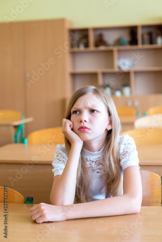 Student sitting at a desk in a classroom looking bored during study time