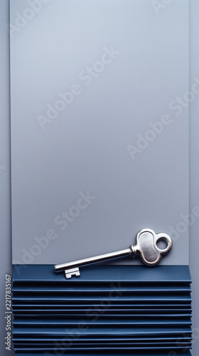 Vintage silver key on grey paper and blue book background