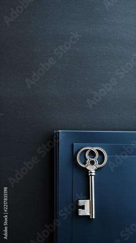 Vintage silver key on dark blue paper sheets background