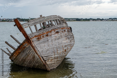abandoned old wooden boat wreck lying on seashore at low tide
