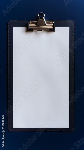 Vertical black leather clipboard mockup with blank white paper on blue background