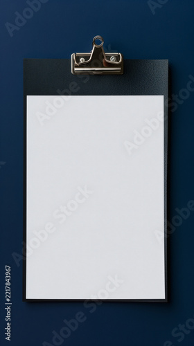 Black leather clipboard with white paper sheet template on blue background