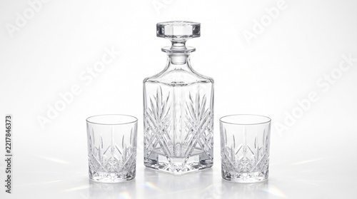 Vintage crystal whiskey decanter and two cut glass tumblers on white background