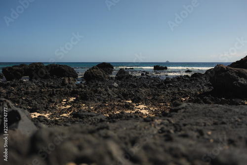 Mojon Blanco Black Volcanic Rocks and Distant Islet