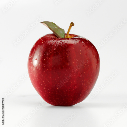 Red apple with leaf and water droplets on white background