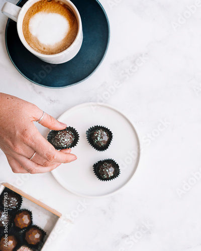 Chocolate bon bons being picked by hand near coffee cup