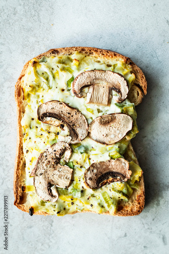 Tarte flambée toast topped with cheese, leeks, and cremini mushrooms