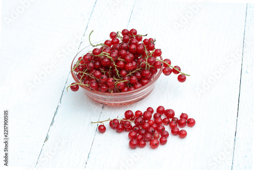 Red Currants in a glass bowl on white wooden surface