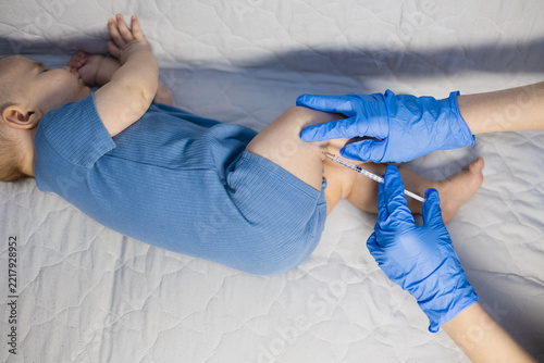 Doctor giving injection with syringe to an infant during routine healthcare procedure.