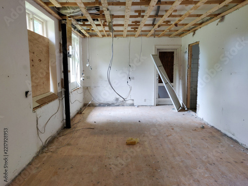 Interior view of a room undergoing renovation with exposed ceiling beams and visible construction materials.