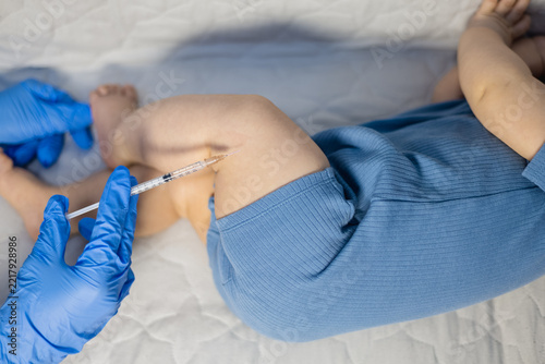 Close up of healthcare worker vaccinating an infant thigh with a syringe.