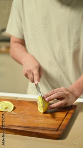 Closeup Man Cutting Fruit on Wooden Cutting Board in Domestic Kitchen