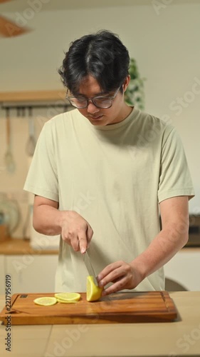 A Man Cutting Lemon on Wooden Cutting Board in Domestic Kitchen