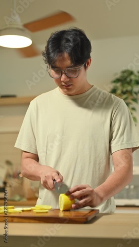 A Man Cutting Lemon on Wooden Cutting Board in Domestic Kitchen