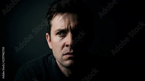 Suspicious man, portrait and face of person with worried expression, doubt and fear on dark background. Serious guy, mystery and intense look for marketing, psychology and storytelling campaign.
