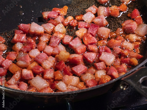 Diced pancetta sizzles and browns inside hot frying pan