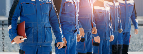 Team of industrial electricians engineers in blue work uniforms standing in line for crew roster and workplace safety banner