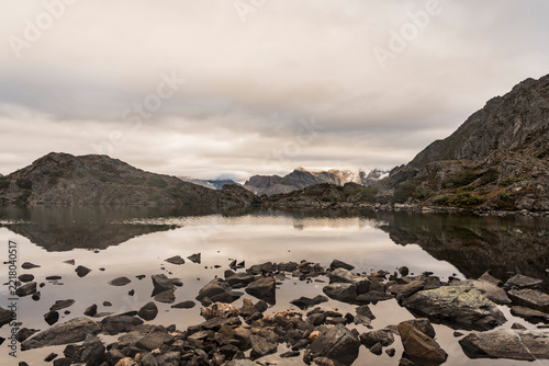 Serene mountain lake with rocky shore and cloud reflections