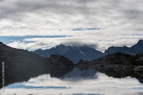 Serene Alpine Lake with Snowy Peaks and Cloud Reflection