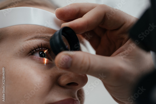 Obraz na plátně Ophthalmologist holding a fundus lens in front of a woman's eye during slit lamp retina examination