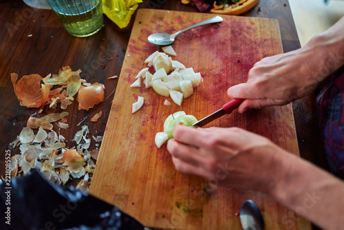 Hands Chopping an Onion on a Wooden Cutting Board in a Kitchen