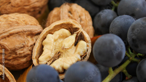 Various walnuts and black grapes on a wooden surface in a kitchen setting