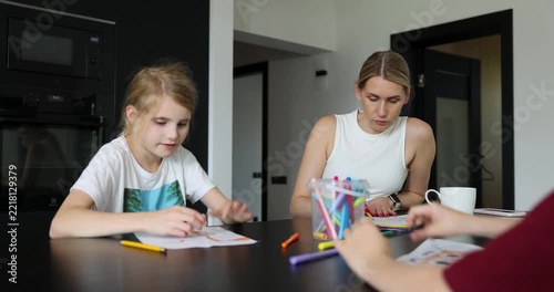 Mother with two children playing drawing game together at home. Quality time