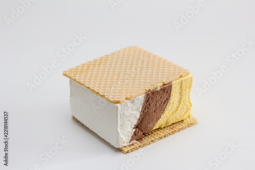 Helado de corte de nata, chocolate y vainilla entre obleas sobre fondo claro