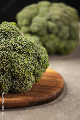 Fresh green broccoli florets on wooden cutting board, close up
