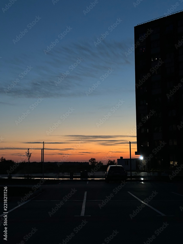 Fototapeta premium Evening sunset skyline over waterfront with silhouetted building and parked car for background and website header design