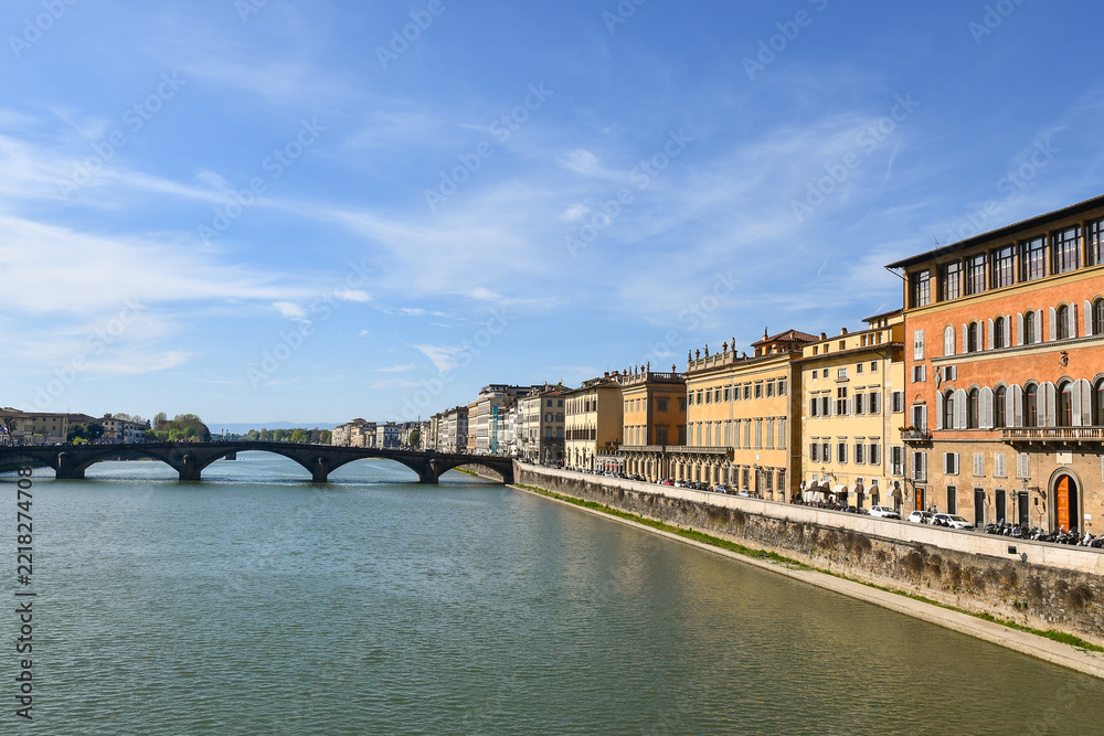 Fototapeta premium Arno river view with historic buildings and Ponte Santa Trinita bridge under blue sky in Florence, Tuscany, Italy