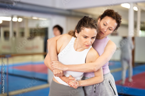 Fotografie Emotional woman trying to escape from back grip and delivering elbow strike to m