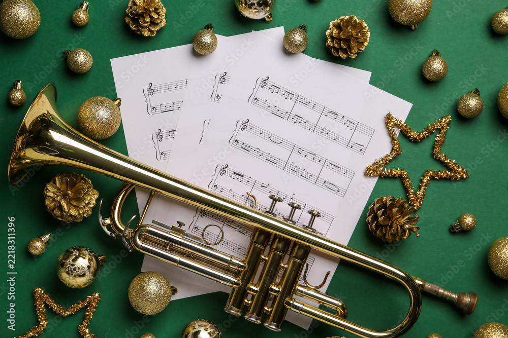 Fototapeta premium Golden trumpet and christmas music sheets with glitter ornaments on green background for holiday celebration, this arrangement evokes the festive spirit of holiday music and seasonal celebrations