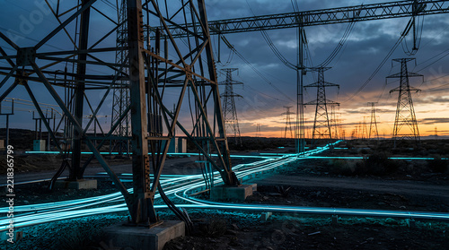 modern high-voltage power transmission lines and glowing fiber optic cables at dusk under a dramatic sky with sunset hues