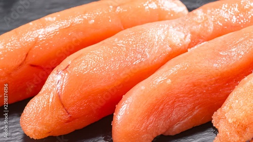 Fresh tarako fish roe glistening on dark slate surface, premium Japanese seafood ingredient for culinary use