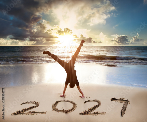  Young man handstand on the beach. happy new year 2027 concept