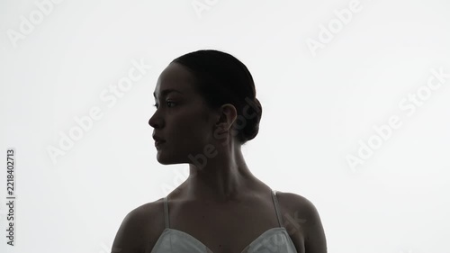 Backlit silhouette of a ballet dancer in contemplative profile during graceful movement
