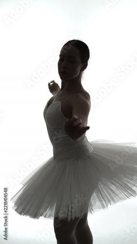 Ballet dancer in white tutu performs graceful movements in studio lighting