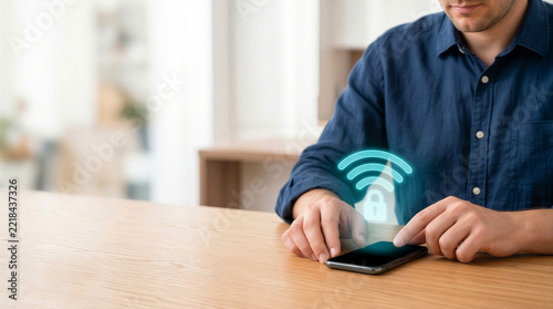 Man using a smartphone with a secure Wi-Fi padlock hologram on a wooden table