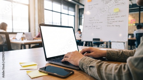 Business professional working on laptop with blank screen at wooden desk