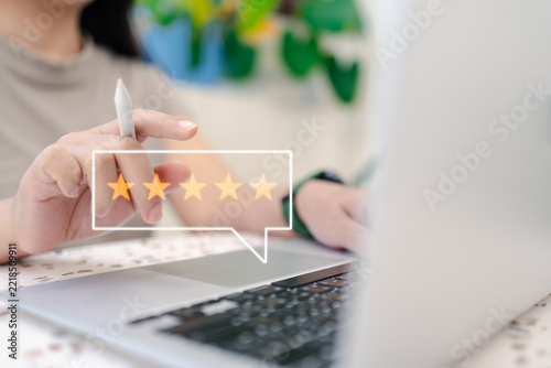 Close up of hands using laptop with glowing five star rating hologram overlay