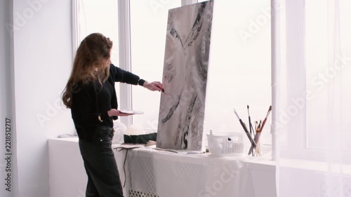 Painter workplace. Abstract art. Woman professional artist using paint palette knife enjoying hobby near window in studio indoor.