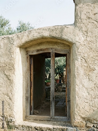 Rustic Mediterranean Stone Archway Doorway with Weathered Wooden Frame and Olive Grove View, Authentic Old World Architecture, Traditional Rural Farmhouse Exterior, Warm Natural Sunlight, Travel Conce