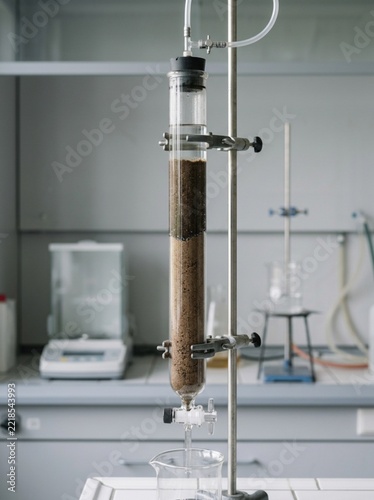 Scientific Soil Filtration Experiment in Laboratory Setting with Glass Column Apparatus, Earth Sample Analysis, Environmental Research, Water Purification Testing, Academic Chemistry Lab Equipment