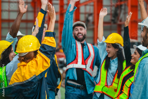 Happy diverse factory workers giving high fives and cheering together to celebrate success