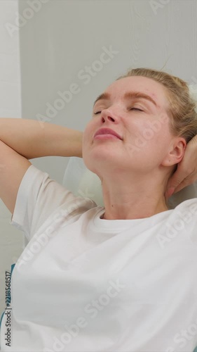 Woman reclines in chair with close up shots of her upper body and face set against simple indoor environment with light gray walls recline relaxation white